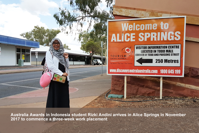 A female student standing in front of Alice Springs signboard